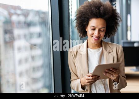 Portrait of a smiling confident african american young businesswoman working with digital tablet Stock Photo