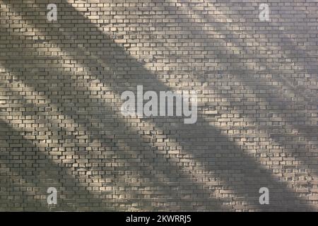 Diagonal shadows and lines falling on a typical common brick wall. Stock Photo