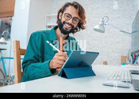 Young designer looking at camera while working with graphics tablet Stock Photo
