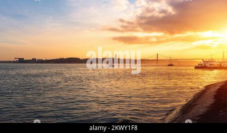 Tagus River (Rio Tejo) at sunset with 25 de Abril Bridge and Sanctuary of Christ the King on background - Lisbon, Portugal Stock Photo