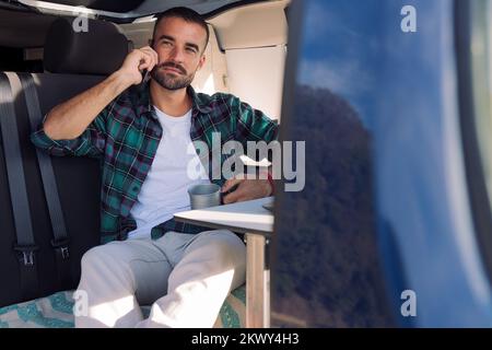 man sitting inside his camper van talking on phone Stock Photo