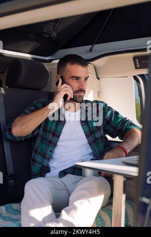 man sitting inside his camper van talking on phone Stock Photo