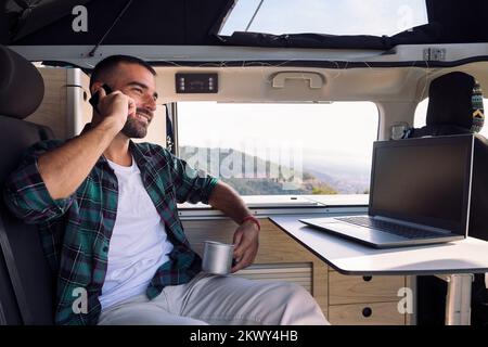 man inside his camper van talking on mobile phone Stock Photo