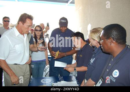 Wildfires,  El Cajon, CA, October 28, 2007   Nick Ho, a Community Relations Specialist from Austin, hands a FEMA assistance information pamphlet to California Governor Arnold Schwarzenegger during his visit Sunday at the Local Assistance Center (LAC) at Cuyamaca College in El Cajon. Other CR Team members looked on as Ho explained FEMA's recovery efforts at the center. FEMA is just one of more than 25 local, county, state, and federal agencies represented at the LAC designed to assist victims of the recent wildfires. FEMA .. Photographs Relating to Disasters and Emergency Management Programs, A Stock Photo