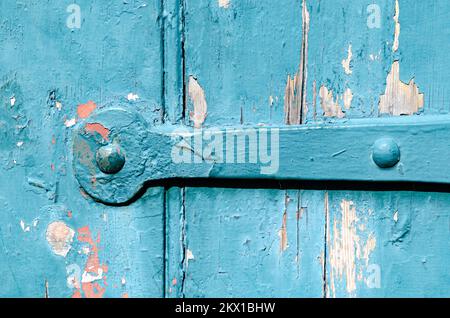 Locks and hinges on an old flaked paint timber door painted green Stock Photo