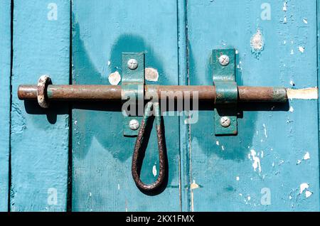 Locks and hinges on an old flaked paint timber door painted green Stock Photo