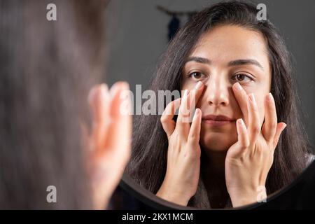 Touching face, millennial brunette woman touching face. Facial skin care, everyday spa treatment concept idea image, enjoy soft moisturized hydrated. Stock Photo