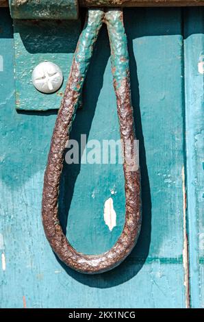 Locks and hinges on an old flaked paint timber door painted green Stock Photo