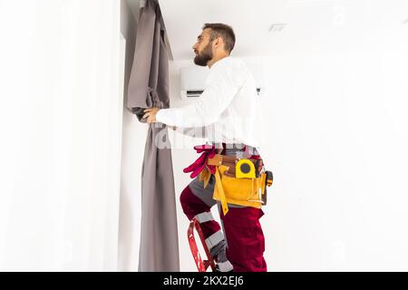 Man hanging window curtain indoors. Interior decor element Stock Photo