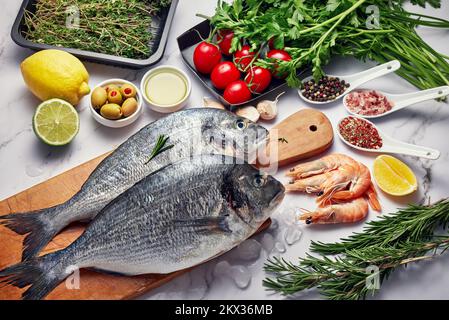 Fresh Fish Food background. Different seafood, shrimps and red caviar. Fish for cooking with herbs, vegetables and spices isolated on white background Stock Photo