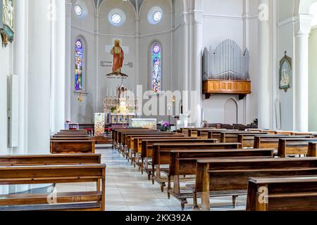 View of pews, altar and organ inside of Divin Maestro - a roman catholic parish church in Alba, Italy. Stock Photo