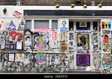 Closed down shop covered in posters and graffiti on Brick Lane, Shoreditch, London Stock Photo