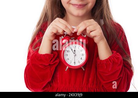 Christmas woman with red alarm clock, smiling girl in red Santa claus dress posing on white background Stock Photo