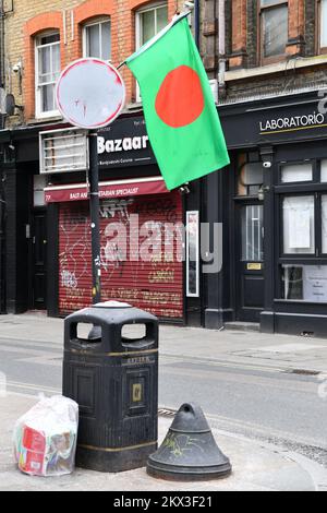 Bangladeshi national flag flying from painted over road sign above a rubbish bin on Brick Lane Shoreditch London Stock Photo