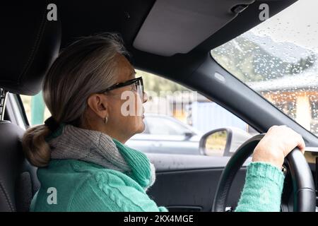 The gray-haired lady drives her own car Stock Photo