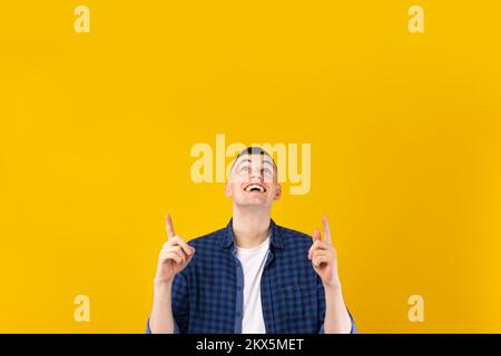 Excited caucasian guy pointing up with both hands at free space for advertisement or text, yellow background Stock Photo