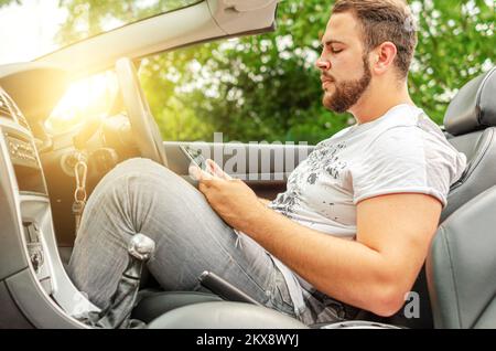 A man with a tablet in a car. Stock Photo
