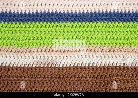 horizontal colored crochet lines pattern, beige, blue, green and brown colors, horizontal rows  close up background Stock Photo