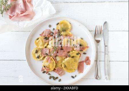 Filled pasta with italian ham, butter and roasted pumpkin seeds on a plate Stock Photo