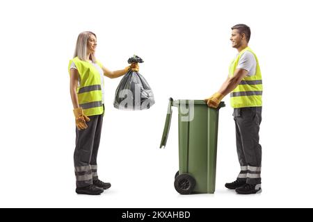 Full length profile shot of a male and female waste collectors putting a bag in a bin isolated on white background Stock Photo