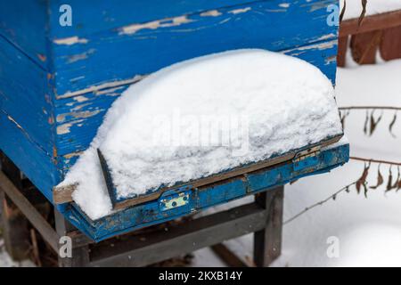 wooden beehive painted in blue and covered with snow, outdoor close up image Stock Photo
