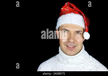 Portrait of happy middle aged man in Santa hat on black background. Christmas celebration, New Year holiday Stock Photo