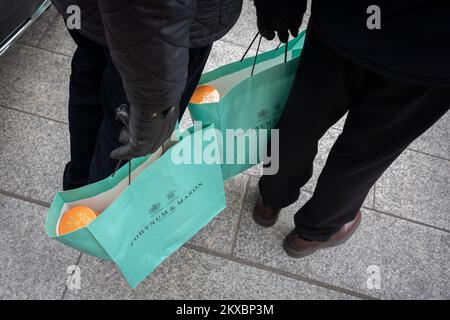 Two male shoppers stand holding the famous green shopping bags from Fortnum & Mason, on 29th November 2022, in London, England. Stock Photo