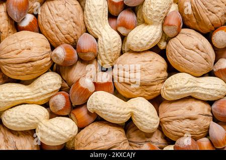 Mixed nuts in their shells, snack nuts, background. Unshelled hazelnuts, peanuts and walnuts, dried and ready to eat. Stock Photo