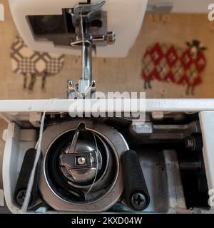 Inner workings of a modern sewing machine looking at how the thread below the presser foot loops the bobbin case below, UK Stock Photo