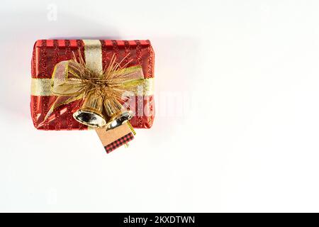 Small red wrapped gift box with ribbon and bells holiday greeting card, room for text on a white background Stock Photo
