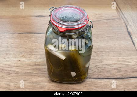Pickled cucumbers with horseradish and garlic in a large glass jar, a traditional Polish dish. Stock Photo