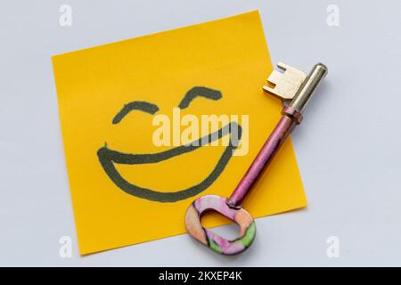 A key to happiness concept with a key and hand drawn happy faces ...