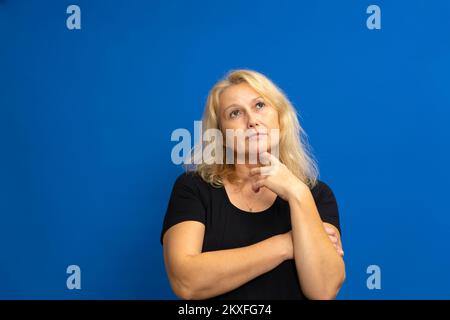 Portrait of cunning curious emotion expressing frankness pretty charming with blonde hair pensive woman planning weekend vacation in black t-shirt Stock Photo