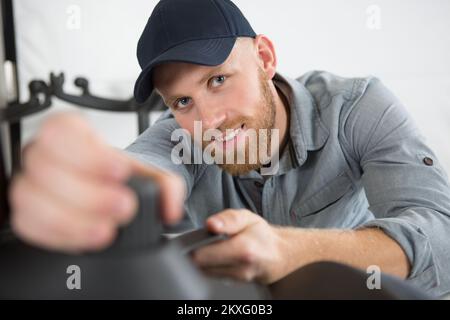 smiling workman reaching forward to grip object Stock Photo