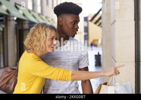 smiling couple looking at clothes in a shop window Stock Photo