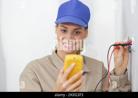 happy female electrician testing a wall socket Stock Photo
