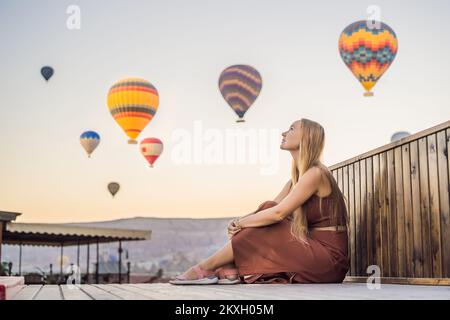 Tourist woman looking at hot air balloons in Cappadocia, Turkey. Happy Travel in Turkey concept. Woman on a mountain top enjoying wonderful view Stock Photo