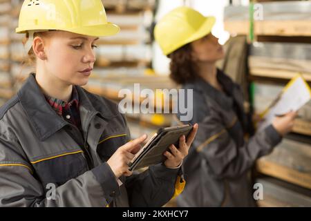 Cute female worker using laptop and seriously looking at screen in warehouse. Stock Photo