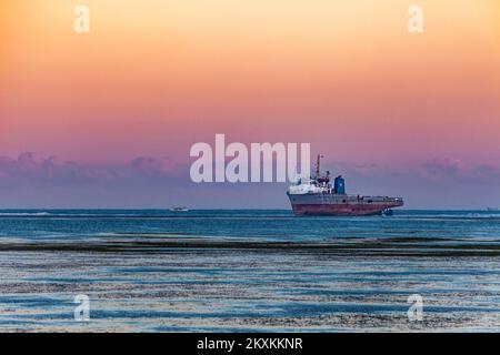 A large ship at dusk, sitting high and dry on the reef off the island of Bali, Indonesia. Stock Photo