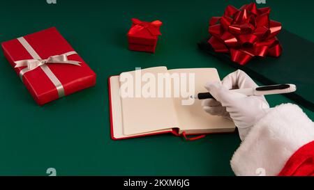 Santa Claus's hands writing his list in horizontal view, copy space for mock up in open agenda Stock Photo