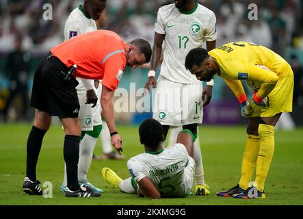 Match referee Michael Oliver checks on the condition of Saudi Arabia's Ali Al-Bulaihi during the FIFA World Cup Group C match at the Lusail Stadium in Lusail, Qatar. Picture date: Wednesday November 30, 2022. Stock Photo