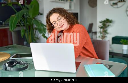 Young smiling woman student using laptop elearning or working at home. Stock Photo