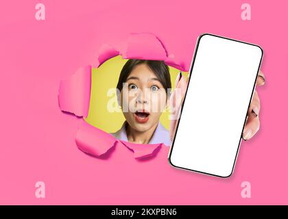 Astonished asian woman showing cell phone, posing in torn Stock Photo