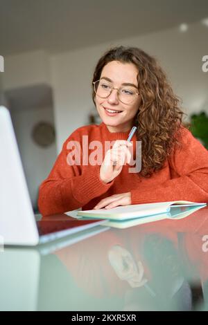 Young woman student using laptop looking at computer elearning at home. Stock Photo