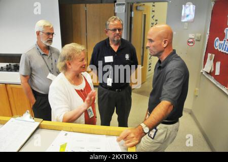 Flooding   Severe Storm - Duluth, Minn. , July 26, 2012   Ceil Strauss (center, left), Minnesota state coordinator for the National Flood Insurance Program (NFIP), talks with Federal Coordinating Officer Mark Neveau (right) and other staff members at FEMA's Minnesota Joint Field Office about flood insurance. The NFIP offers flood insurance to homeowners, renters, and business owners if their community participates in the program. Participating communities agree to adopt and enforce ordinances that meet or exceed FEMA requirements to reduce the risk of flooding. Norman Lenburg/FEMA. Minnesota S Stock Photo