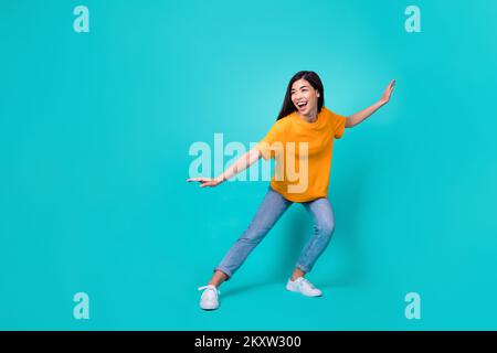 Full size photo of pretty brunette lady dance look promo wear t-shirt jeans shoes isolated on teal color background Stock Photo