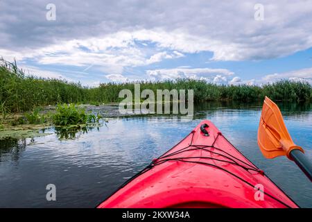 Kayaker point of view with beautiful landscape. Kayak bow with a view on the river and rushes.   River kayaking concept. Active vacations in wild natu Stock Photo