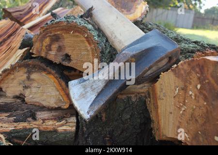 Firewood on wood block. Heavy axe lies near it. Stock Photo