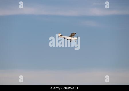 Small private single-propeller plane flying over the blue sky. Agricultural aviation. Stock Photo