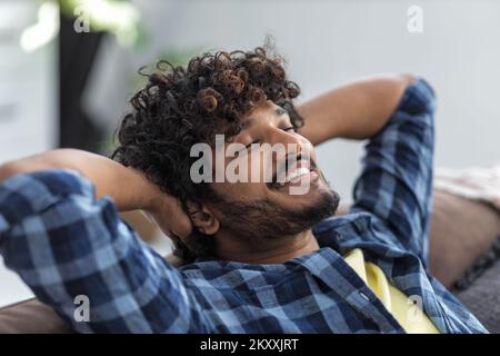 Relax at home, positive thinking concept. Portrait of happy asian man lying on sofa resting Stock Photo